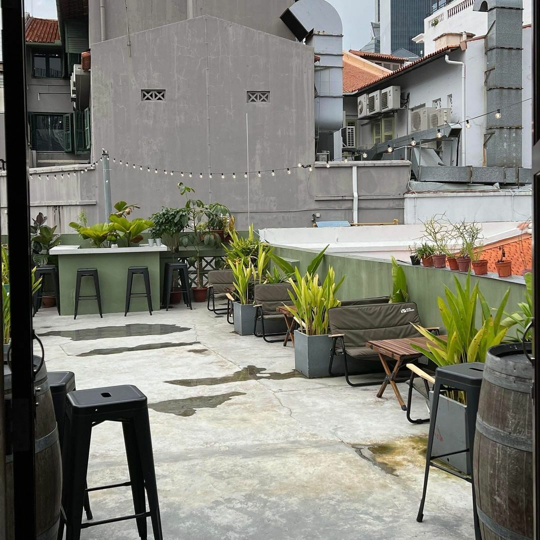 best affordable rooftop bar - The Otherside - outdoor rooftop seating area with plant decorations and camping furniture