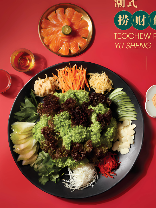 A big Yusheng platter and a small salmon platter are served beside glasses of Chinese tea. 